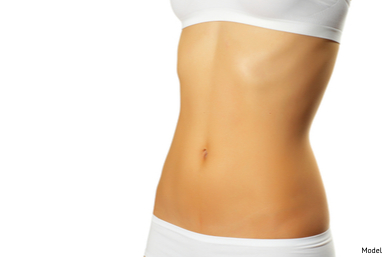 Woman baring her flat abdomen with firmness akin to tummy tuck results.