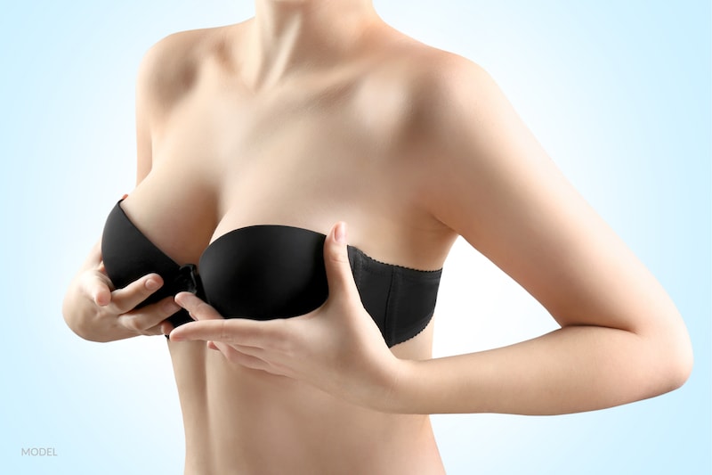 Woman with her hands under her breasts giving them a subtle breast lift.