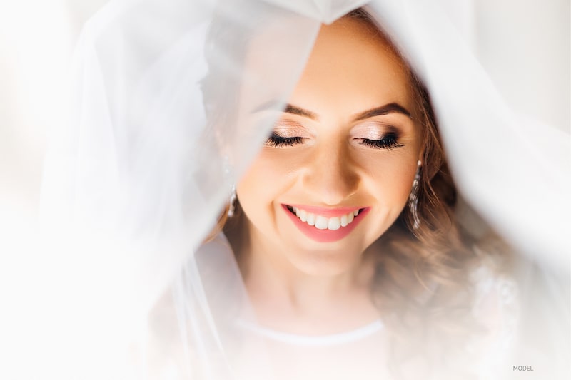 Woman's face smiling under a wedding veil.