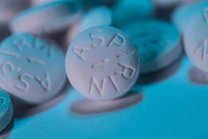 Collection of aspirin pills on a blue counter.