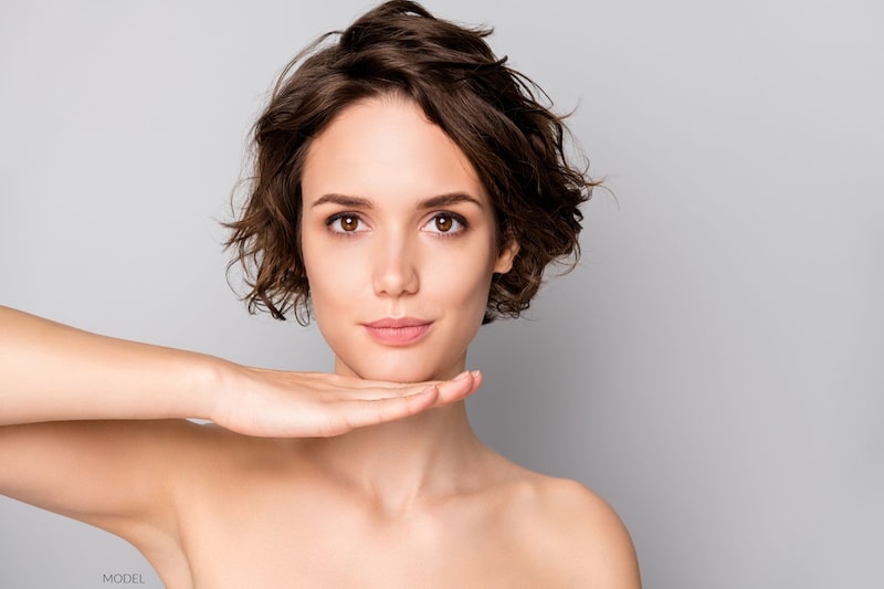 Beautiful, young woman staring at the camera with a hand under her chin.