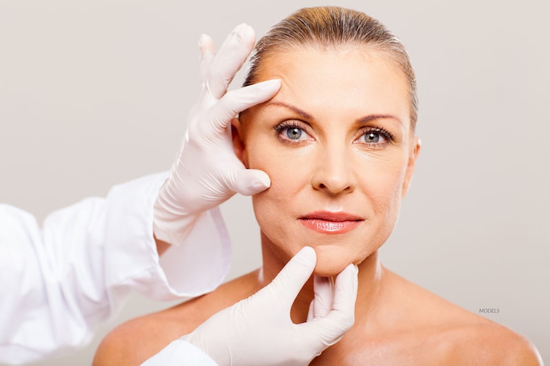 Middle-aged woman whose face is being examined by a doctor