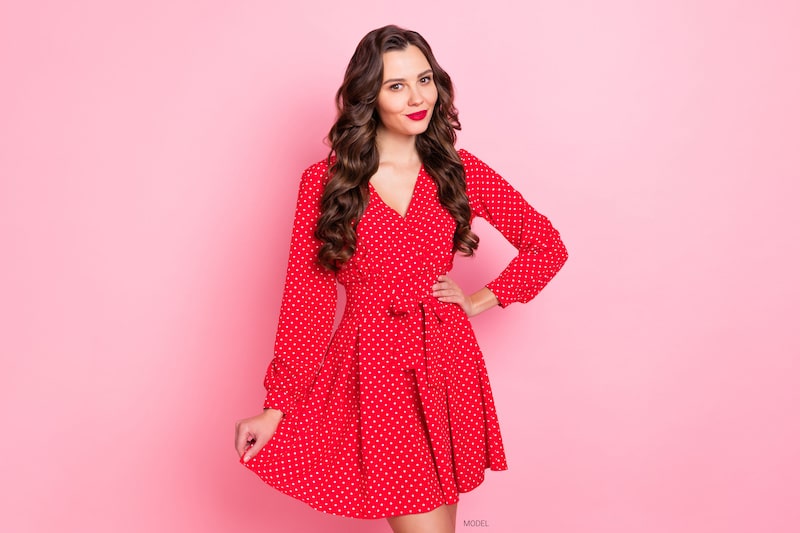 Beautiful young woman with brown hair and wearing a red dress